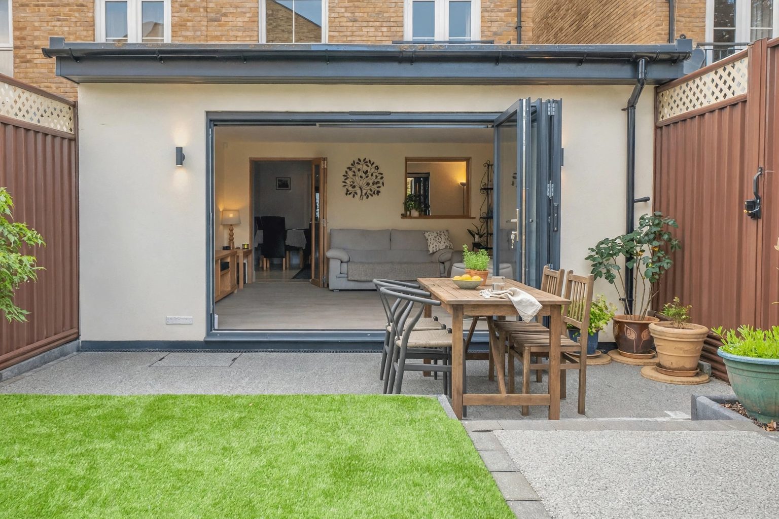 Single-storey home addition and extension with bifold glass doors opening onto a paved patio and green lawn in a Toronto backyard by Renofy